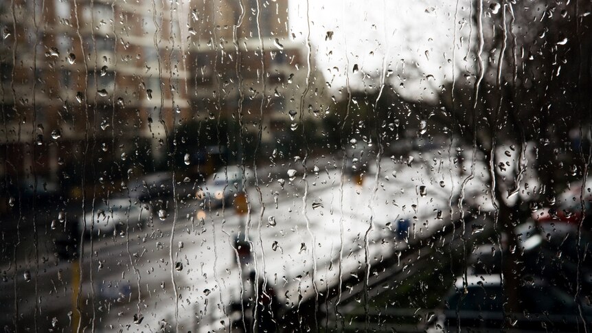 A view of a city street and apartment block through a rain covered window