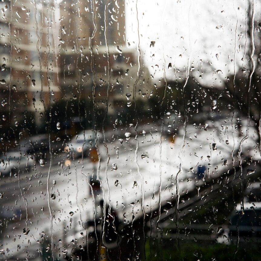 A view of a city street and apartment block through a rain covered window