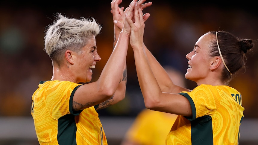 Michelle Heyman holding hands with another matildas player. 