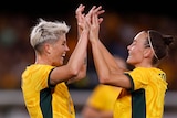 Michelle Heyman holding hands with another matildas player. 