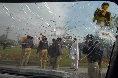 Pakistani policemen gather beside the wreckage of a police van (AFP: Arif Ali)
