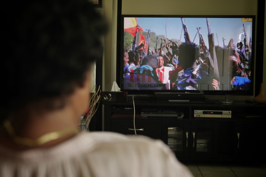 a woman watching people fighting on television