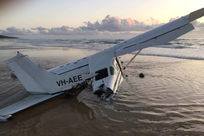 The wreckage of a light plane sits in shallow water on the beach of Fraser Island.