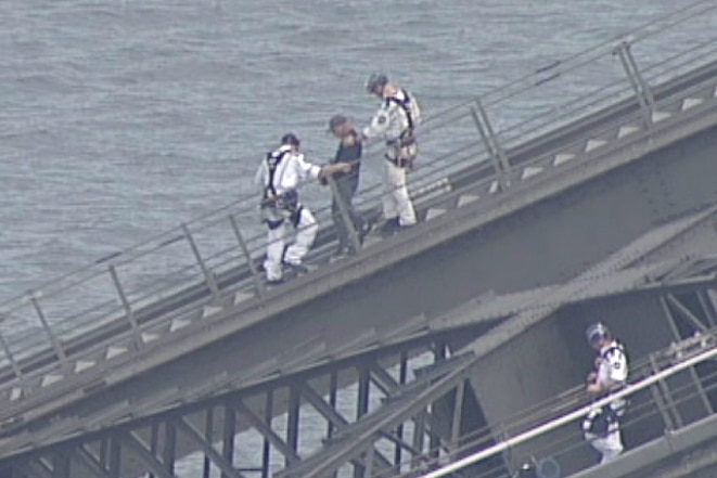 Police escort a man down the slope of the bridge.