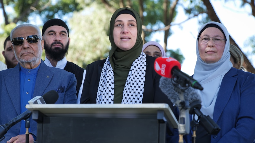 A group of Muslim leaders gather together in a line in a park