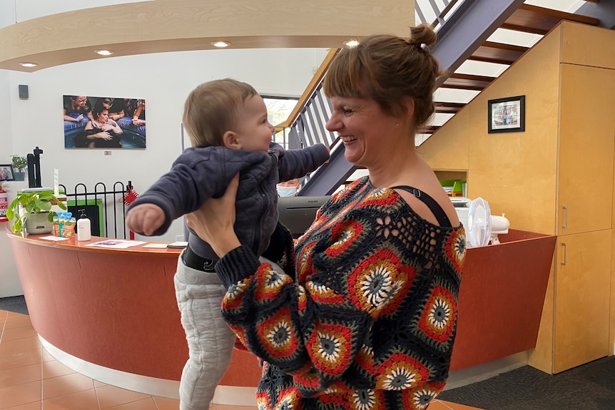 A laughing woman looks at her smiling toddler.