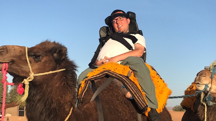 Cory sits on top of a camel