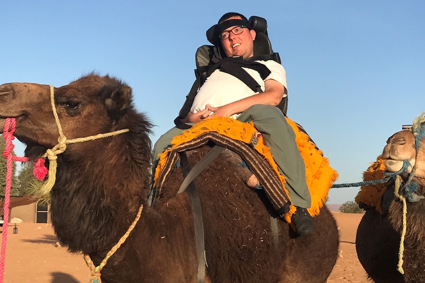 Cory sits on top of a camel