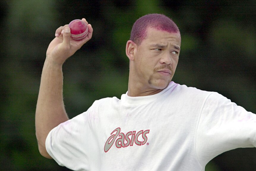 A young Andrew Symonds, with his hair dyed maroon, throws a cricket ball