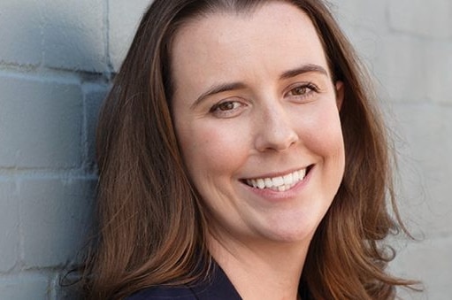 A woman with brown hair smiles.