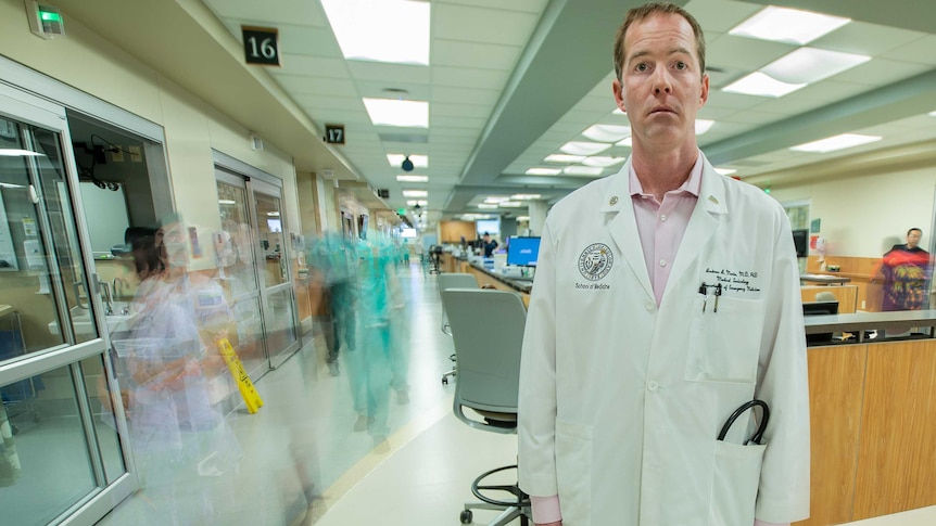 A man in a lab coat stands in a hospital