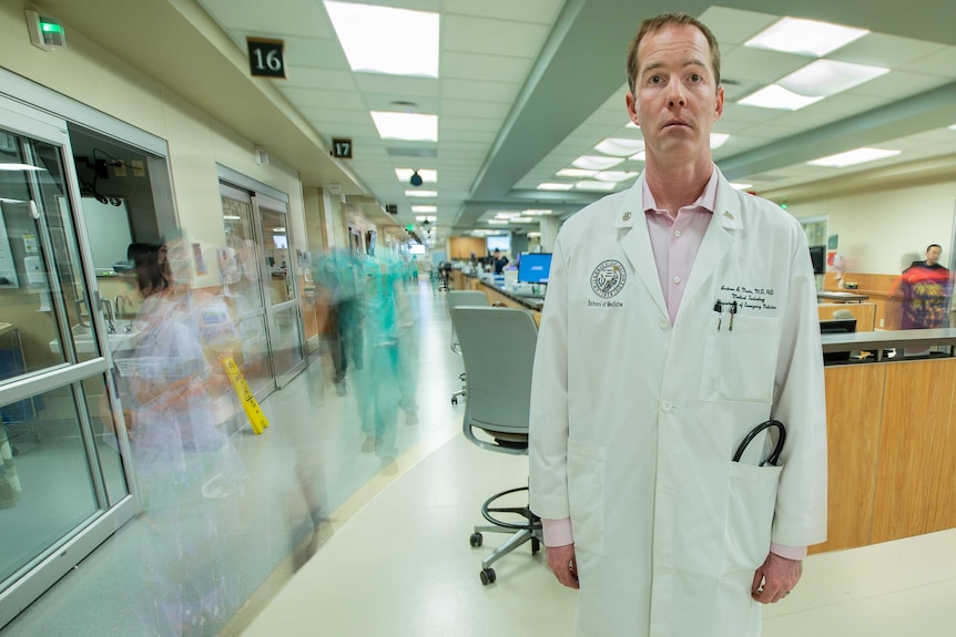 A man in a lab coat stands in a hospital