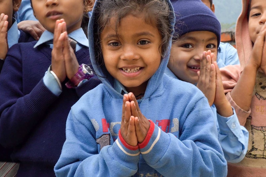Children hold up their hands in prayer.