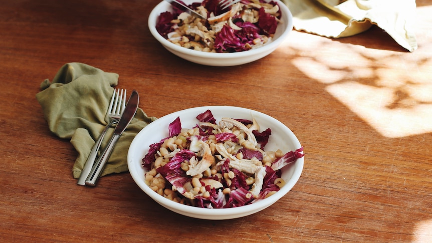 Two bowls of chicken, cannellini beans and radicchio on a dining table, a lighter meal for spring nights.