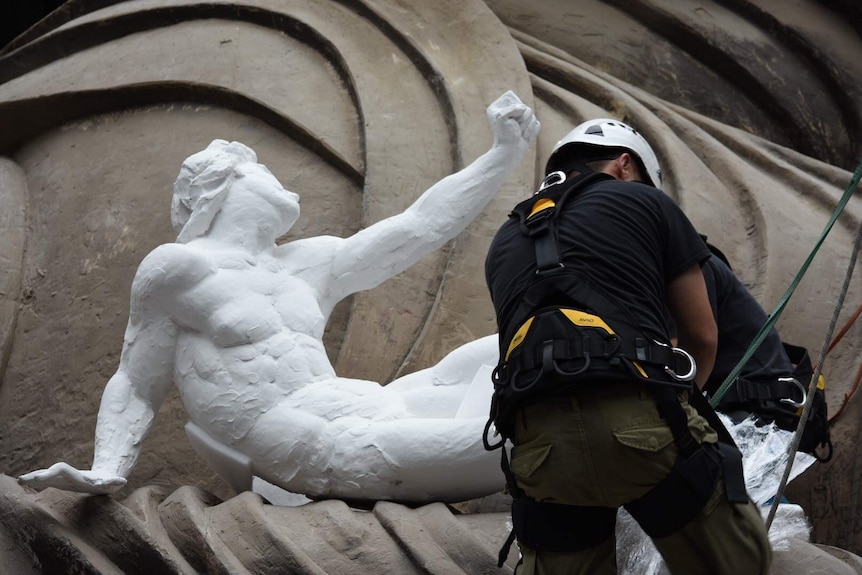 A Chinese worker carefully unwraps a classical sculpture as it is installed as part of a larger work of art at the NGV.