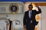 Barack Obama walks out of a plane.