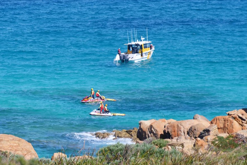 A search boat and two jet skis on the water near rocks at Injidup Beach, south of Yallingup.