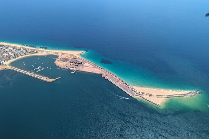 Aerial view of an outcrop of sand and concrete in the middle of blue ocean waters.