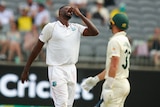 Jason Holder pinches his nose and leans his head back as Marnus Labuschagne looks on blurred in the foreground