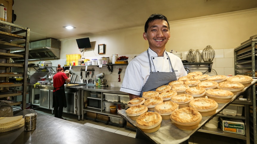 Chan Khun holding a tray of pies.