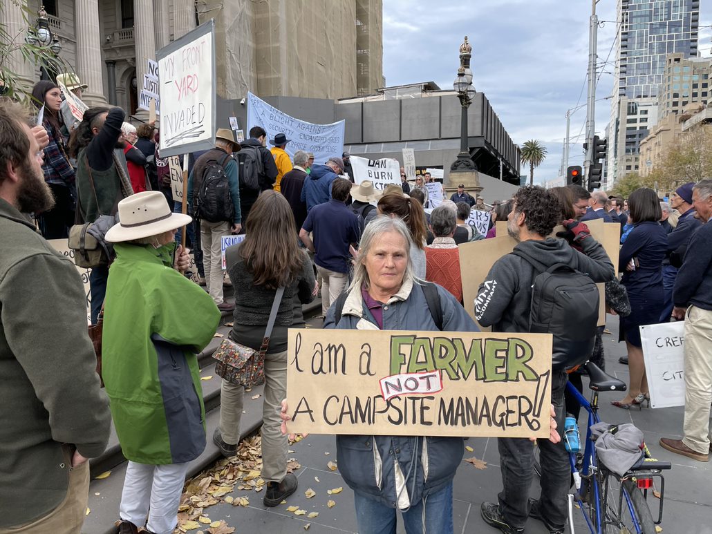 Farmer holding up sign I am a farmer not a camp site manager