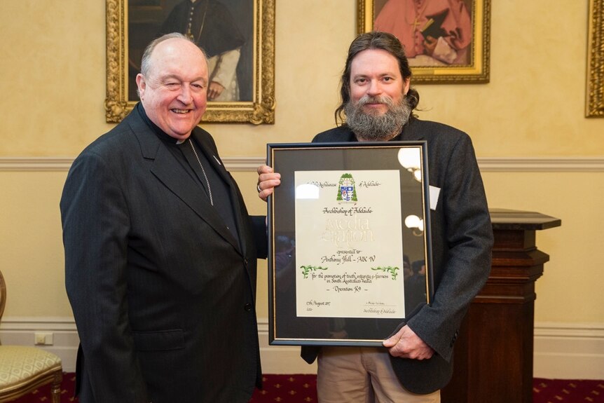 Archbishop Wilson presents framed certificate to Tony Hill.