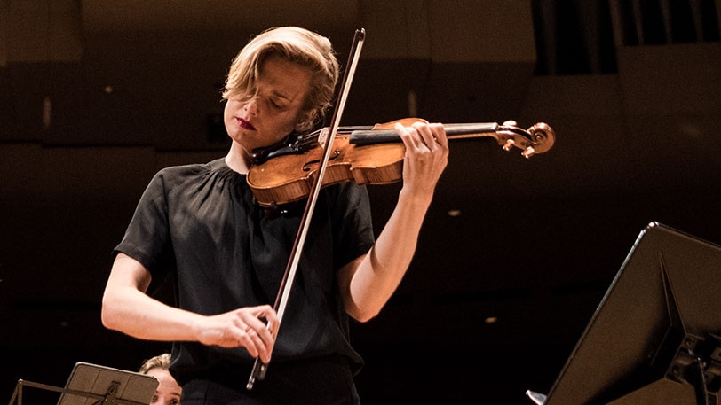 Close up shot of ACO Principal Violin Satu Vänskä playing onstage with a focussed expression.