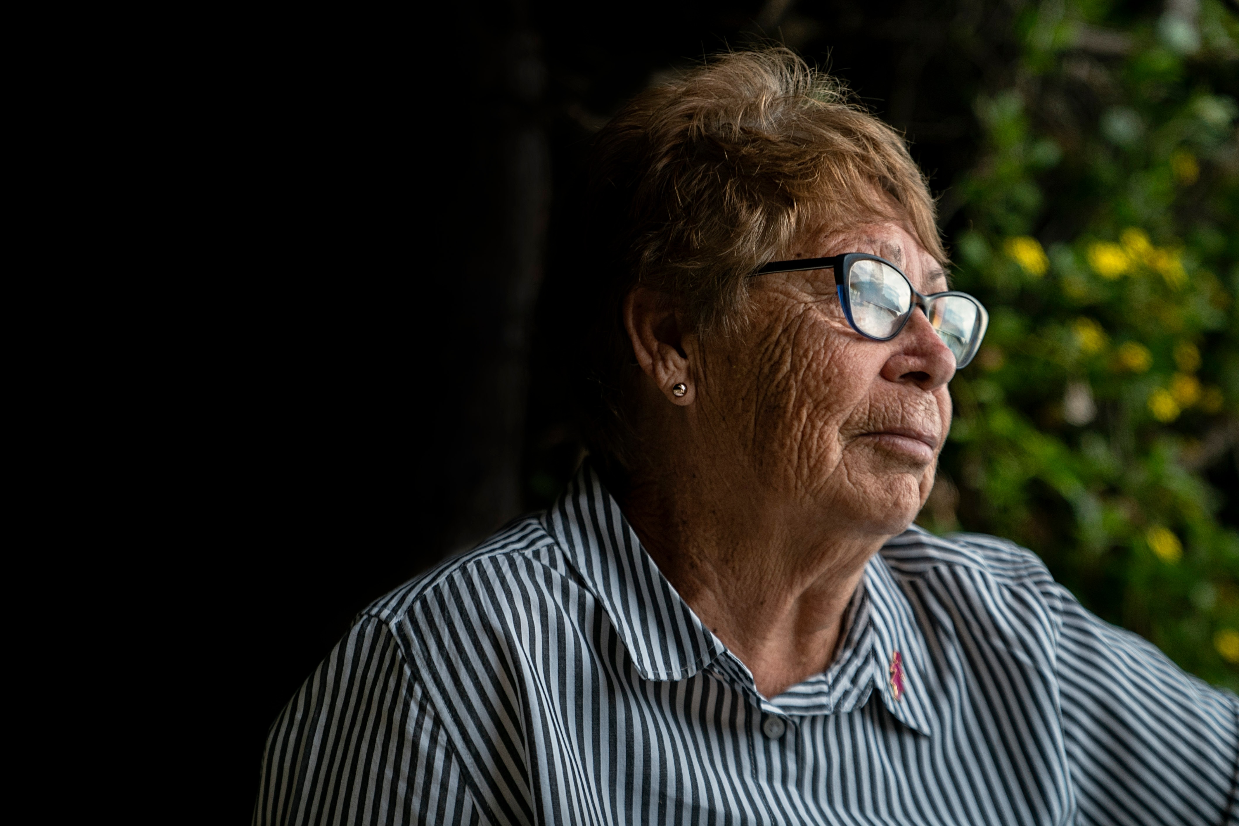 Side-on portrait shot of a woman wearing glasses starting off into the distance.