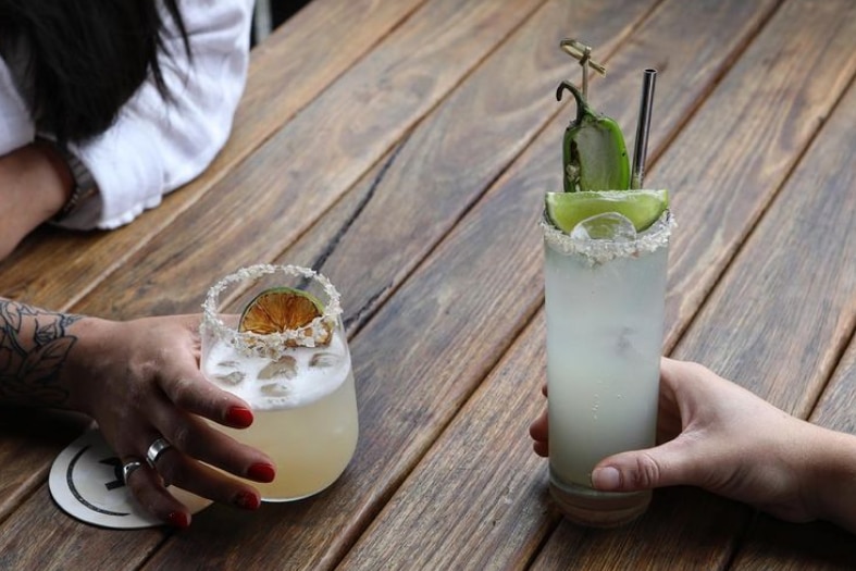 Two cocktails on a wooden table.