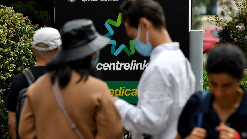 Several people stand in a queue at a Centrelink office.