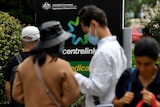 Several people stand in a queue at a Centrelink office.