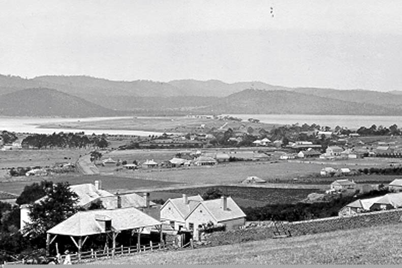 a black and white historic photo of glenorchy, showing some houses and farmland