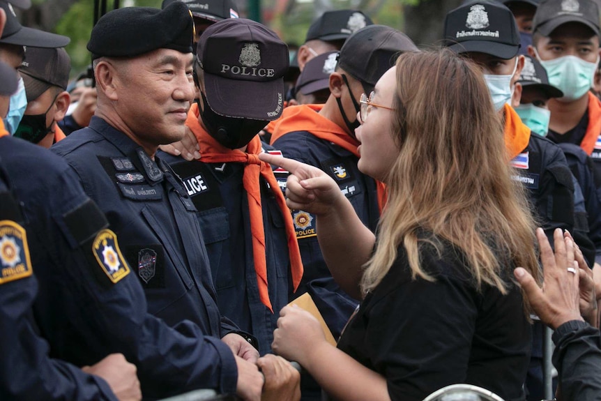 A young woman points her finger at a row of policemen