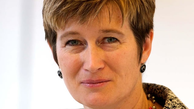 A woman with short hair smiles as she looks at the camera for a professional headshot.