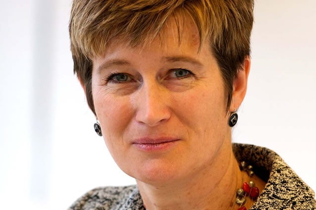 A woman with short hair smiles as she looks at the camera for a professional headshot.