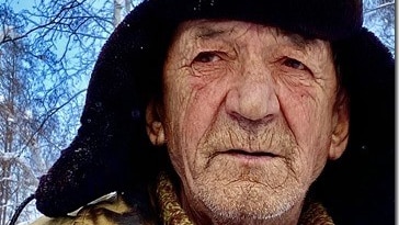 A Russian horse herder, an older man wearing a winter hat and jacket.