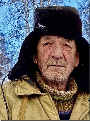 A Russian horse herder, an older man wearing a winter hat and jacket.