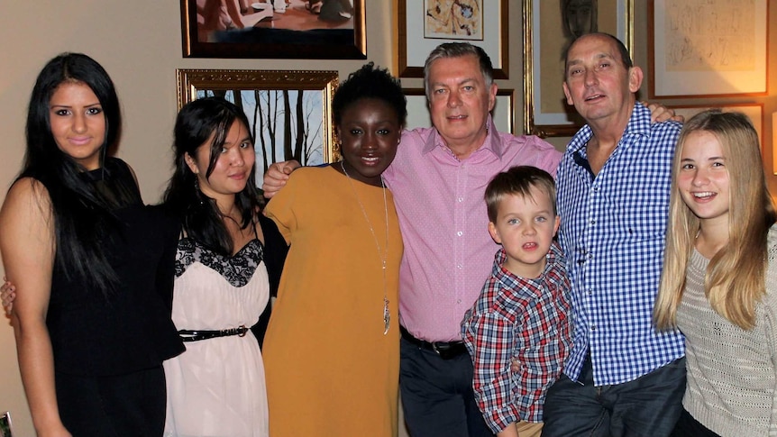 John Guthrie and his partner Dennis Cash with their adopted son Liam and some of the girls they have fostered.