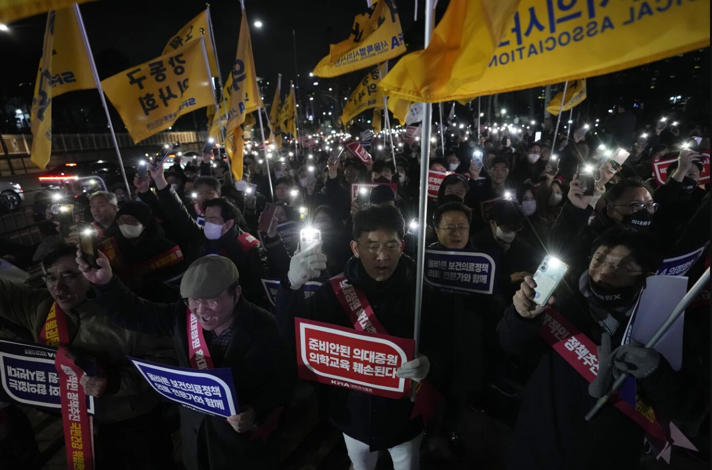 A crowd of people holding their smartphones and signs