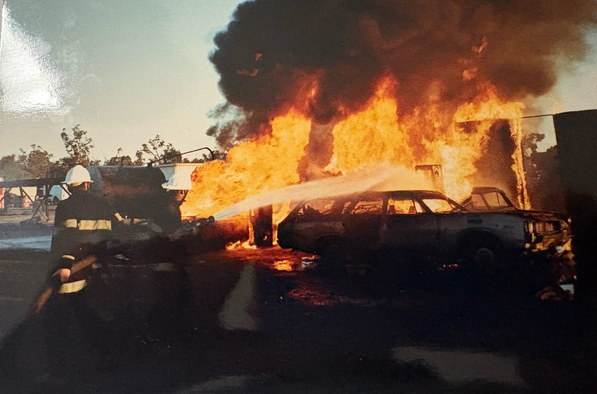 Un bombero dirige agua de una manguera hacia un coche en llamas. 