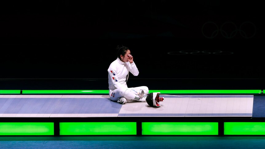 Shin A Lam sits on the piste after being defeated by Britta Heidemann in their epee semi-final.