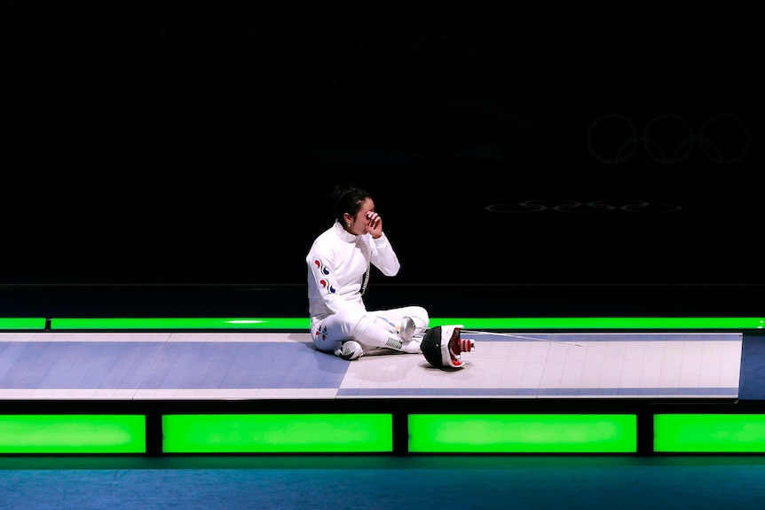 Shin A Lam sits on the piste after being defeated by Britta Heidemann in their epee semi-final.
