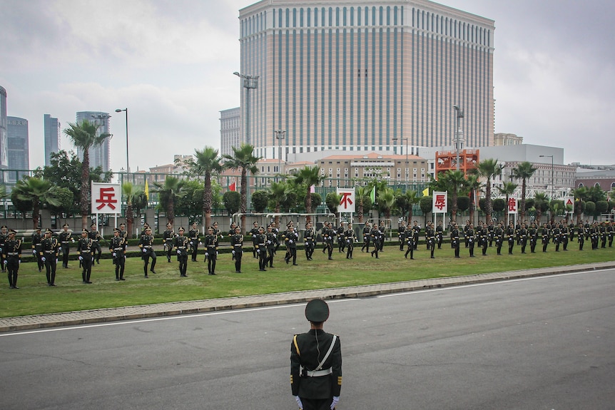 A troops of soldiers perform in front of a casino. 