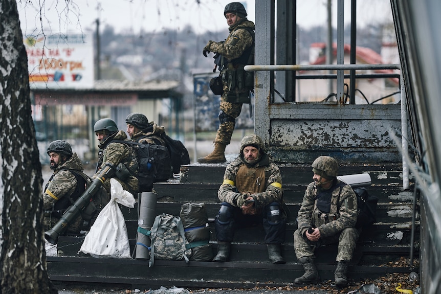 Six soldiers are leaning on the steps of a building.