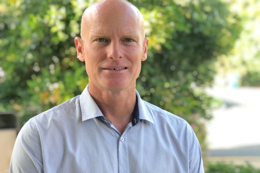 Man wearing business shirt standing looking at the camera, close, slight smile