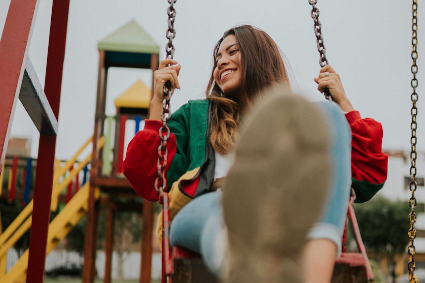 Woman sitting on swings in park