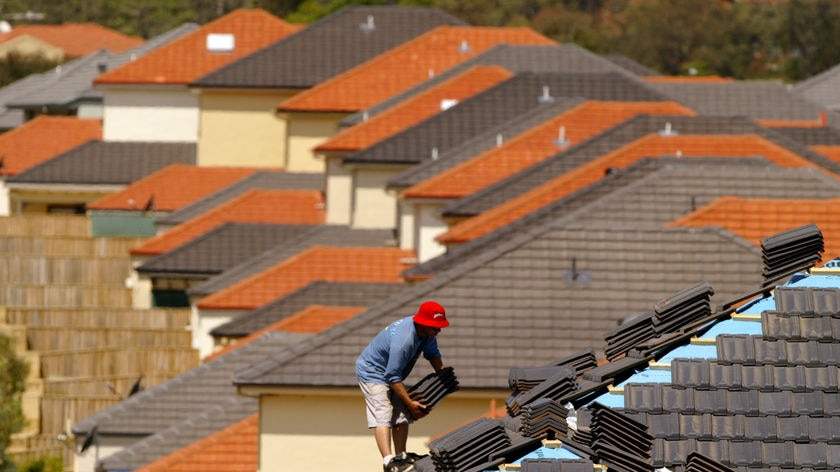 An Australian worker places tiles on the roof of a house in north western Sydney.