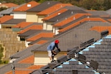 An Australian worker places tiles on the roof of a house in north western Sydney.