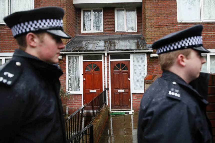 Police stand outside the flat of suspected Jihadi John