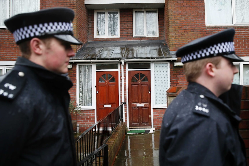 Police stand outside the flat of suspected Jihadi John